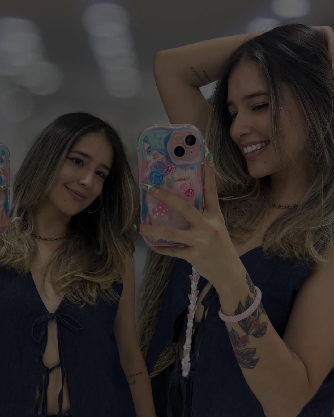 Dos amigas se toman una selfie en el espejo del salón con cabello en capas y ondas