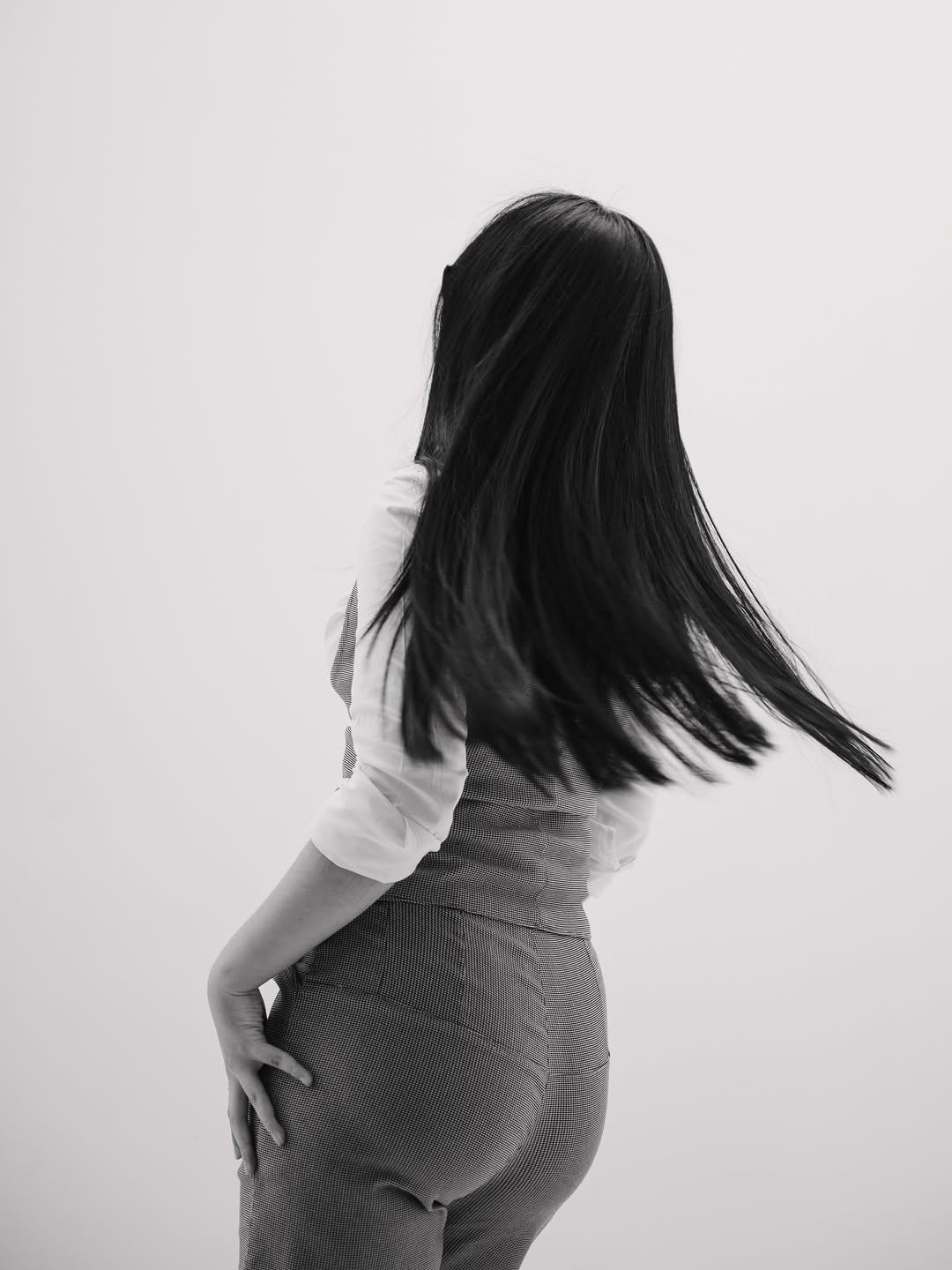 Modelo de espaldas girando con el cabello negro en movimiento