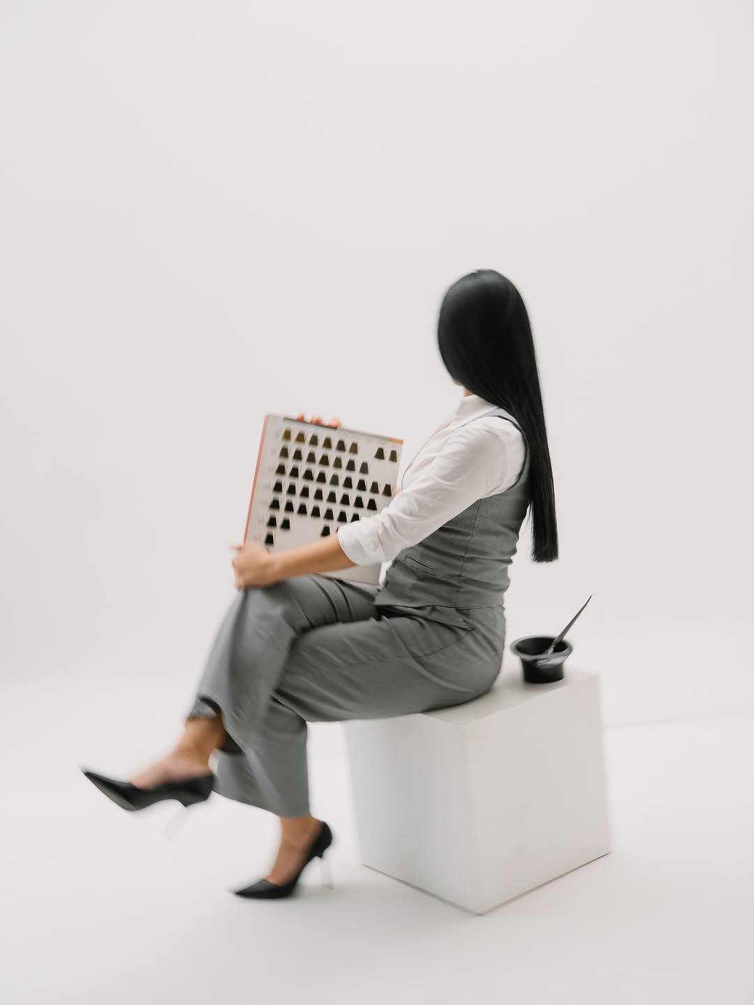 Modelo sentada en un cubo blanco con la carta de tonos